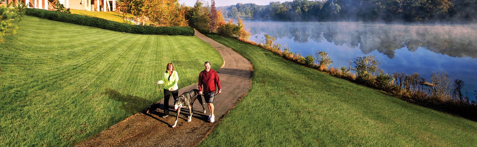Couple walking dog along lakeside trail in Sterling on the Lake