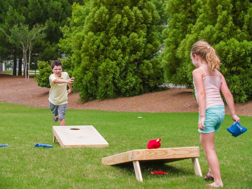 Boy and girl playing cornhole at the linear park at Sterling on the Lake