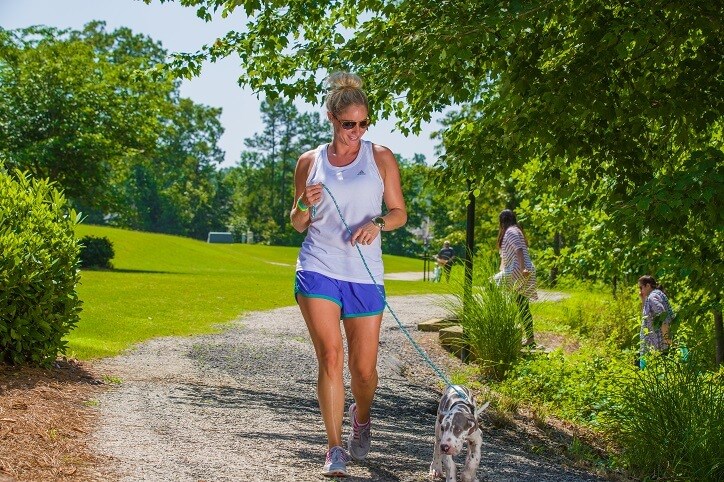 Woman walking puppy on the trails at Sterling on the Lake