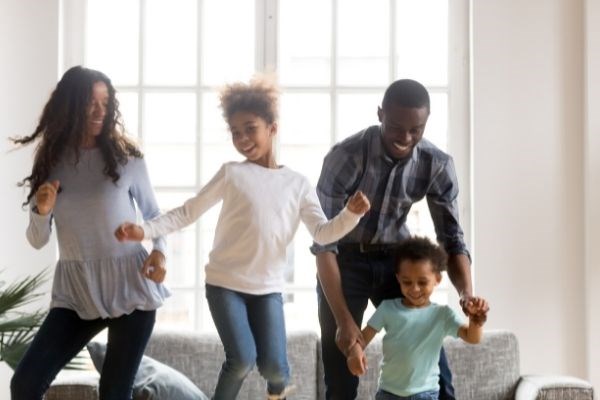 Family of four dancing in living room